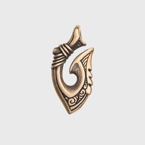 May include: A gold-colored metal pendant in the shape of a traditional Hawaiian fish hook, known as a "hei"