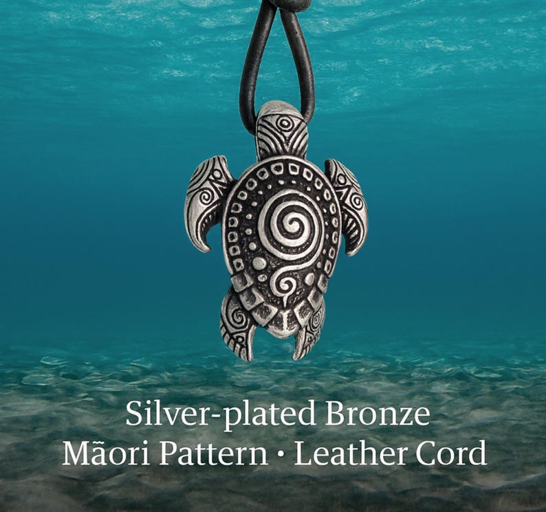 May include: Silver-plated bronze turtle pendant with a Māori pattern, on a black leather cord. The pendant has detailed spiral and dot patterns. The background is a blue underwater scene.
