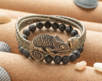 May include: A green leather bracelet with a black lava rock bead bracelet and a gold chameleon charm.