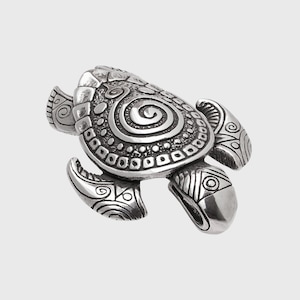May include: A silver-coloured turtle figurine with detailed carvings. The shell features a spiral design and other intricate patterns. The flippers and head also have detailed carvings. The figurine is set against a plain background.