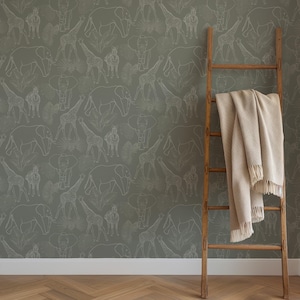 May include: A green wallpaper with a white outline pattern of various animals, including elephants, giraffes, and zebras. A wooden ladder with a beige blanket draped over it is in front of the wallpaper.