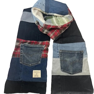 Puede incluir: Una larga bufanda de patchwork hecha de mezclilla y tela a cuadros. La bufanda tiene dos bolsillos y está forrada con un material suave y peludo. La etiqueta dice "Reworked by Ruthie".