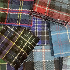 Op de afbeelding: Assortiment van stoffen vierkanten in verschillende ruitpatronen, waaronder rood, blauw, groen en zwart.