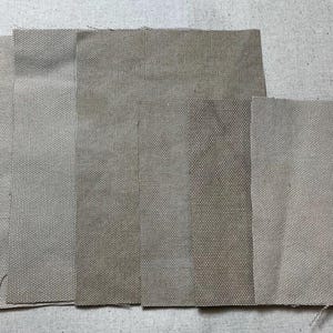 Puede incluir: Cinco muestras de tela diferentes en varios tonos de beige y marrón. La tela tiene una textura tejida.