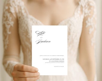 Può includere: Un invito di nozze bianco con una scrittura elegante. L'invito recita "Kate e Jackson" e include la data, l'ora e il luogo del matrimonio: St. Augustine's Church. L'invito è tenuto da una persona che indossa un abito di pizzo bianco.