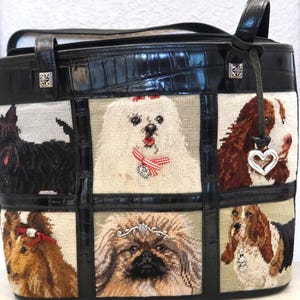 May include: Black leather tote bag with a patchwork design featuring embroidered dog portraits. The bag has a black crocodile-embossed leather trim and handles, with silver-tone hardware and a heart-shaped charm.