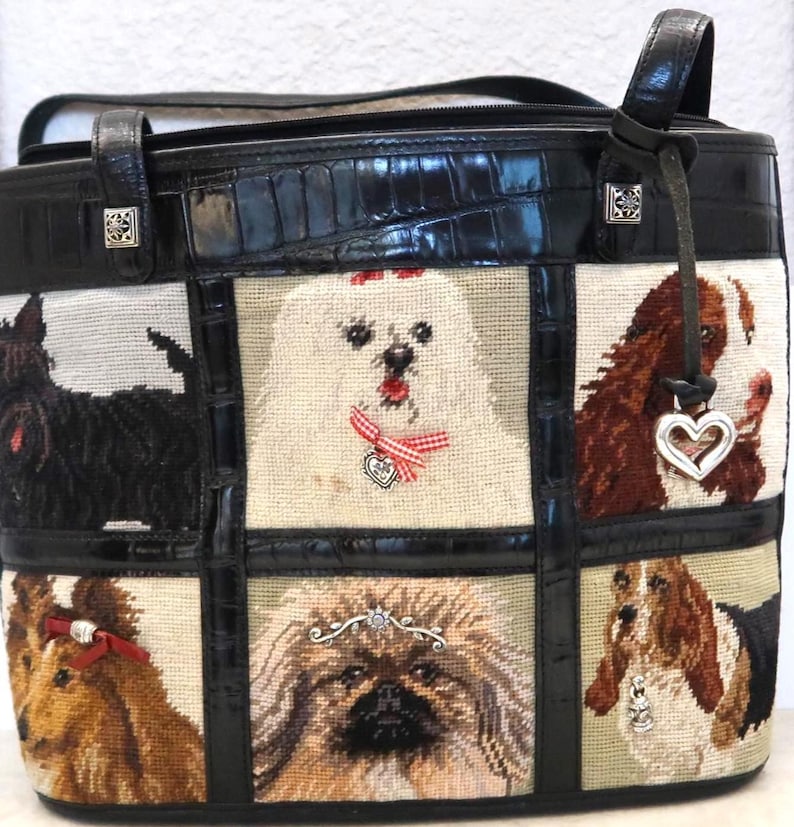 May include: Black leather tote bag with a patchwork design featuring embroidered dog portraits. The bag has a black crocodile-embossed leather trim and handles, with silver-tone hardware and a heart-shaped charm.