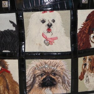 May include: Black leather tote bag with a tapestry design featuring various dog breeds. The bag has a black leather handle and trim, with silver-tone hardware. The tapestry panels showcase detailed portraits of different dogs.