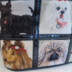 May include: Tote bag featuring a tapestry design with various dog breeds. The bag has a black leather trim and handle. The tapestry includes a black Scottish Terrier, a white dog with a red bow, a brown and white dog, and a fluffy dog.