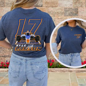 K&ouml;nnte beinhalten: Ein marineblaues T-Shirt mit einer gro&szlig;en orangefarbenen und blauen Nummer 17 auf der R&uuml;ckseite. Die Nummer ist wei&szlig; umrandet und enth&auml;lt ein Rennwagen im Inneren. Der Text "KYLE LARSON" befindet sich unter der Nummer. Das Shirt wird von einer Person mit einer blauen Jeans getragen.
