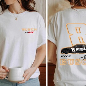 Puede incluir: Camiseta blanca con una imagen en blanco y negro de un coche de carreras con el n&uacute;mero 8 y las palabras "Kyle Busch" y "Rebel" en ella. La camiseta tambi&eacute;n tiene las palabras "Busch" y "MCH" en la parte delantera.