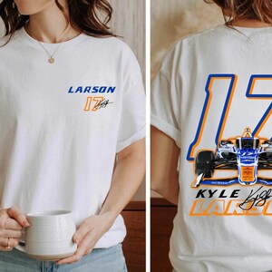 K&ouml;nnte beinhalten: Wei&szlig;es T-Shirt mit einem blauen und orangenen Rennwagen-Design auf der R&uuml;ckseite. Der Wagen ist die Nummer 17 und der Text "KYLE LARSON" befindet sich unter dem Wagen. Die Vorderseite des Shirts tr&auml;gt den Text "LARSON 17" in Blau und Orange.