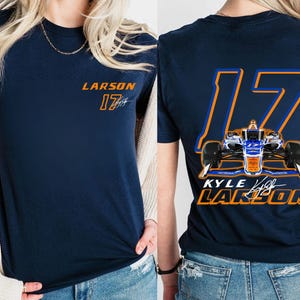 K&ouml;nnte beinhalten: Marineblaues T-Shirt mit einer wei&szlig;en und orangenen Nummer 17 und dem Text "LARSON" auf der Vorderseite. Die R&uuml;ckseite des Shirts zeigt ein Rennwagen mit der Nummer 17 und dem Text "KYLE LARSON".
