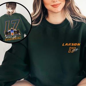 K&ouml;nnte beinhalten: Ein dunkelgr&uuml;ner Pullover mit einem wei&szlig;en und orangenen Design mit der Nummer 17 und dem Namen "LARSON" auf der Vorderseite. Die R&uuml;ckseite des Pullovers hat ein gr&ouml;&szlig;eres Design mit einem Rennwagen und dem Text "KYLE LARSON" in Wei&szlig; und Orange.