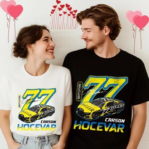 May include: A white and black t-shirt featuring a yellow and blue graphic of a race car with the number 77. The text "Carson Hocevar" is below the car. The shirts are worn by a couple.