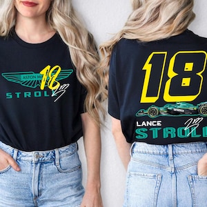 May include: Black t-shirt featuring the Aston Martin logo and the number 18 in yellow. The front of the shirt displays the text "Aston Martin Stroll" in teal and white. The back of the shirt has a teal race car graphic and the name "Lance Stroll".