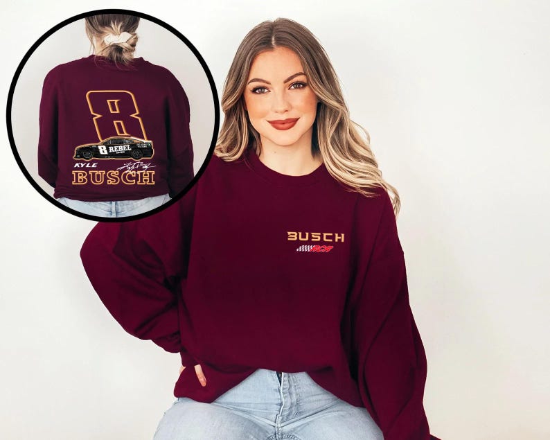 Puede incluir: Sudadera color burdeos con un dise&ntilde;o de franja de carreras blanca y roja y el texto "Busch" en la parte delantera. La parte posterior de la sudadera presenta un coche de carreras con el n&uacute;mero 8 y el texto "Kyle Busch".