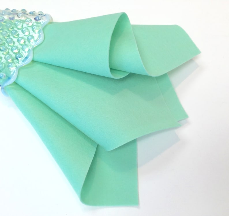 May include: A folded piece of light green felt fabric. The fabric is smooth and has a soft texture.