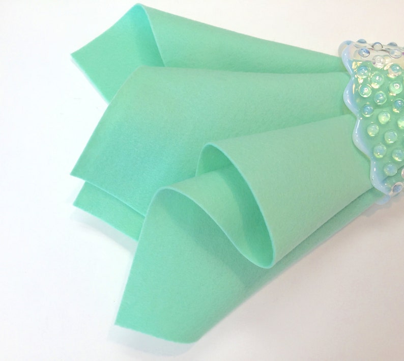 May include: A folded piece of light green felt fabric. The fabric is soft and smooth, and it is ideal for crafting projects.