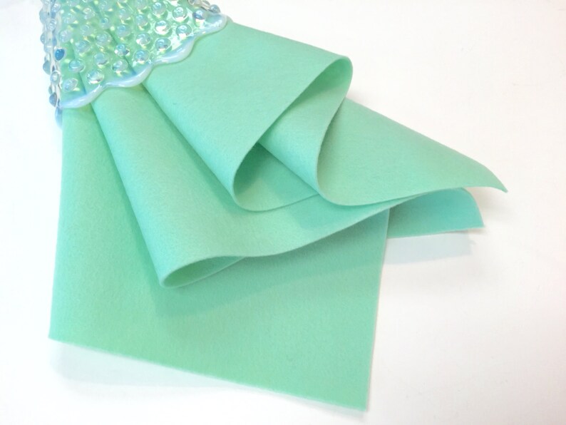 May include: A folded piece of light green felt fabric. The felt is smooth and has a soft texture.