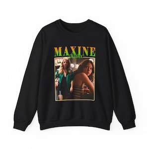 May include: Black sweatshirt featuring a graphic of two women with the text "MAXINE Minx" in green and yellow. The image is a vintage-style design. The sweatshirt is a crew neck style.