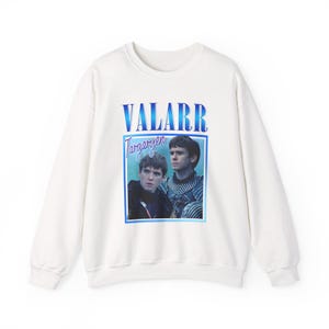 以下が含まれることがあります： 白のスウェットシャツ。青と白のグラフィックが特徴で、「VALARR Targaryen」の文字と2人の男性の写真がプリントされています。カジュアルで快適な衣服です。