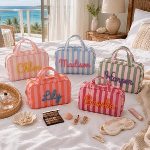 May include: Five rectangular striped cosmetic bags with top handles and personalized names in cursive script. The bags feature vertical stripes in pink, blue, orange, green, and red, with names Chloe, Madison, Harper, Lily, and Brooke in raised lettering.