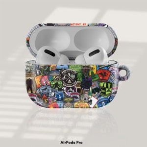 May include: AirPods Pro case decorated with a vibrant assortment of patches depicting cryptids and monsters, with text including "Area 52". The case is open, showing white earbuds.