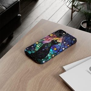May include: A black phone case with a stained glass design featuring a black cat and stars on a rainbow background.