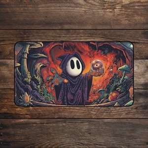 May include: A rectangular mouse mat depicting a hooded figure with a white face and black oval eyes, holding a crystal ball. The background is a vibrant scene with mushrooms, plants, and a fiery red and orange cave.