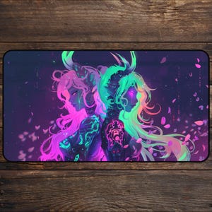 May include: A rectangular desk mat featuring a digital art illustration of two figures with long hair and horns, back-to-back. The figures are in shades of pink and green, with intricate glowing details. The background is dark with floating petals.