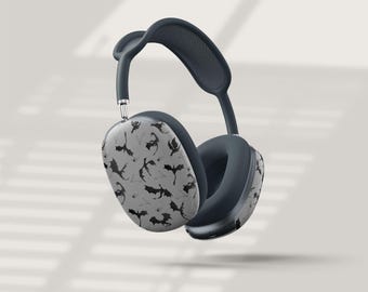 May include: A pair of over-ear headphones in a dark gray color scheme. The earcups feature a light gray surface with a repeating pattern of black bat silhouettes. The headband and earcups are padded for comfort.