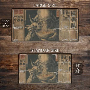 May include: A rectangular playmat with an illustration of a creature eating noodles. Available in two sizes: 39.4 cm x 80 cm and 35.6 cm x 61 cm. The design incorporates Japanese text and zones for a card game, labeled 'Battlefield' and 'Graveyard'.