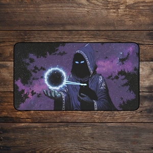 May include: A rectangular desk mat featuring a hooded figure in a dark purple robe against a cosmic nebula background. The figure has glowing blue eyes and holds a glowing orb in one hand while a black cat with glowing blue eyes sits nearby.