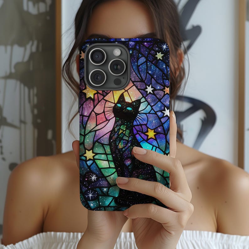 May include: A black cat with blue eyes is silhouetted against a colorful stained glass background with stars. The phone case is made of a hard plastic material and has a glossy finish.