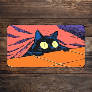 May include: A rectangular black cat illustration peeking from under a blanket. The cat has large yellow eyes and blue ears. The blanket is orange and pink, with a purple border. The background is a dark wood grain.