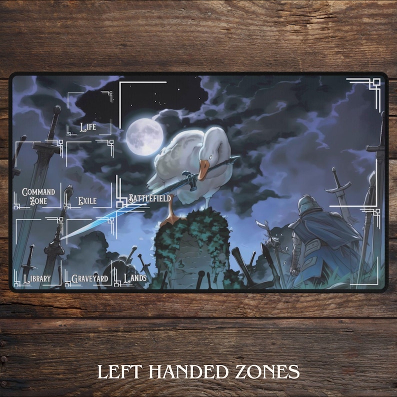 May include: A rectangular playmat featuring a fantasy scene with a goose holding a sword, a full moon, and various zones labeled for a card game. The mat has a dark background with swords and figures, and the text "LEFT HANDED ZONES".