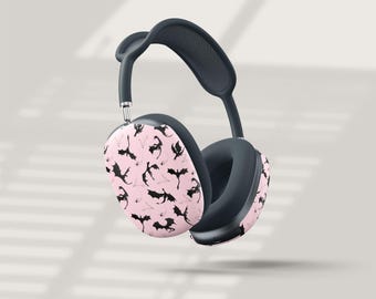 May include: Wireless over-ear headphones with a black and pink design. The earcups are light pink with a repeating pattern of black bat silhouettes. The headband and earcups are dark gray.