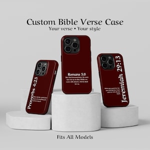 May include: Burgundy phone cases with Bible verses Proverbs 4:23, Romans 5:8, and Jeremiah 29:13 printed in white. The cases are displayed on white pedestals, with the text "Custom Bible Verse Case" above. The phrase "Fits All Models" is at the bottom.