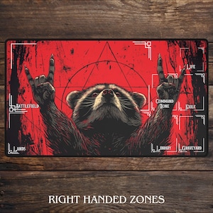 Peut inclure: Tapis de jeu rectangulaire avec un fond rouge et une illustration de raton laveur. Le raton laveur fait un geste de la main rock and roll. Le tapis porte le texte blanc "Battlefield", "Lands", "Command Zone", "Exile", "Life", "Library" et "Graveyard".