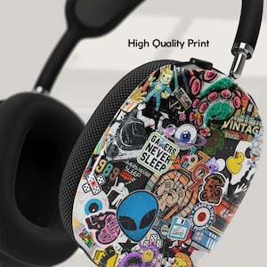 Puede incluir: Auriculares negros con un dise&ntilde;o de calcoman&iacute;as coloridas que presenta una variedad de gr&aacute;ficos, incluyendo un extraterrestre, una mano y el texto "Gamers Never Sleep".