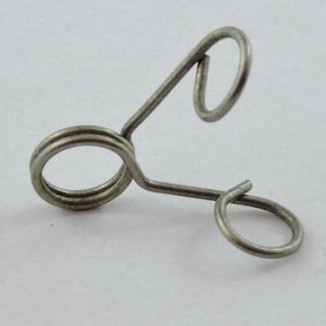 May include: A silver metal spring clip with two loops. The clip is designed to hold items together.