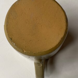 May include: A brown stoneware mug with a handle. The mug has a glazed finish and is slightly speckled.