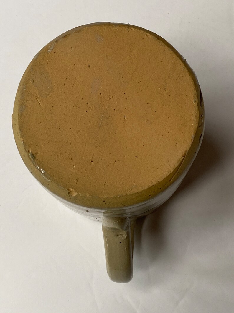 May include: A brown stoneware mug with a handle. The mug has a glazed finish and is slightly speckled.