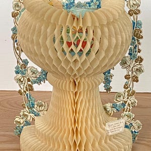 May include: A vintage Valentine's Day card made of paper honeycomb. The card is shaped like a vase with a floral design and the text "Roses sweet as a lover's vow, But yours are sweetest of all to me."