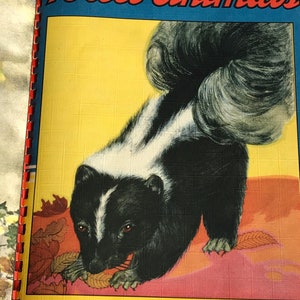 May include: A black and white skunk with a bushy tail is eating a brown leaf. The skunk is on a pink and yellow background with brown leaves. The text "Forest Animals" is at the top of the image. The text "Copyright 1943 by The Saalfield Pub. Co. Made in U.S.A. Akron, O." is at the bottom of the image.