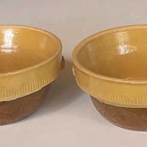 May include: Two yellow and brown ceramic bowls with a textured rim. The bowls have a glazed finish and are perfect for serving soup or salad.