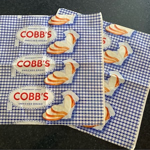 May include: Three vintage blue and white checkered paper bags with the text "Everybody Loves Cobb's Enriched Bread" and a picture of sliced bread.