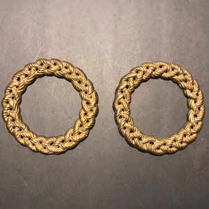 May include: Two gold-colored metal rings with a rope-like design. The rings are about 2 inches in diameter.
