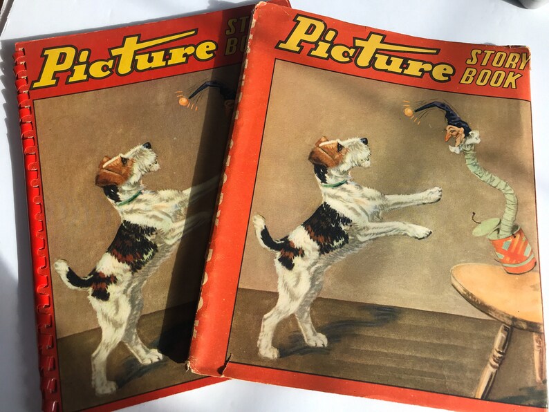 May include: Two vintage red Picture Story Book covers featuring a black and white fox terrier jumping for a ball. The cover on the left has the text "Picture Story Book" in black letters. The cover on the right has the text "Picture Story Book" in black letters.